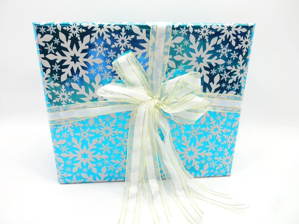 Front view of Maybelline snowflake-themed gift box with white ribbon, festive presentation