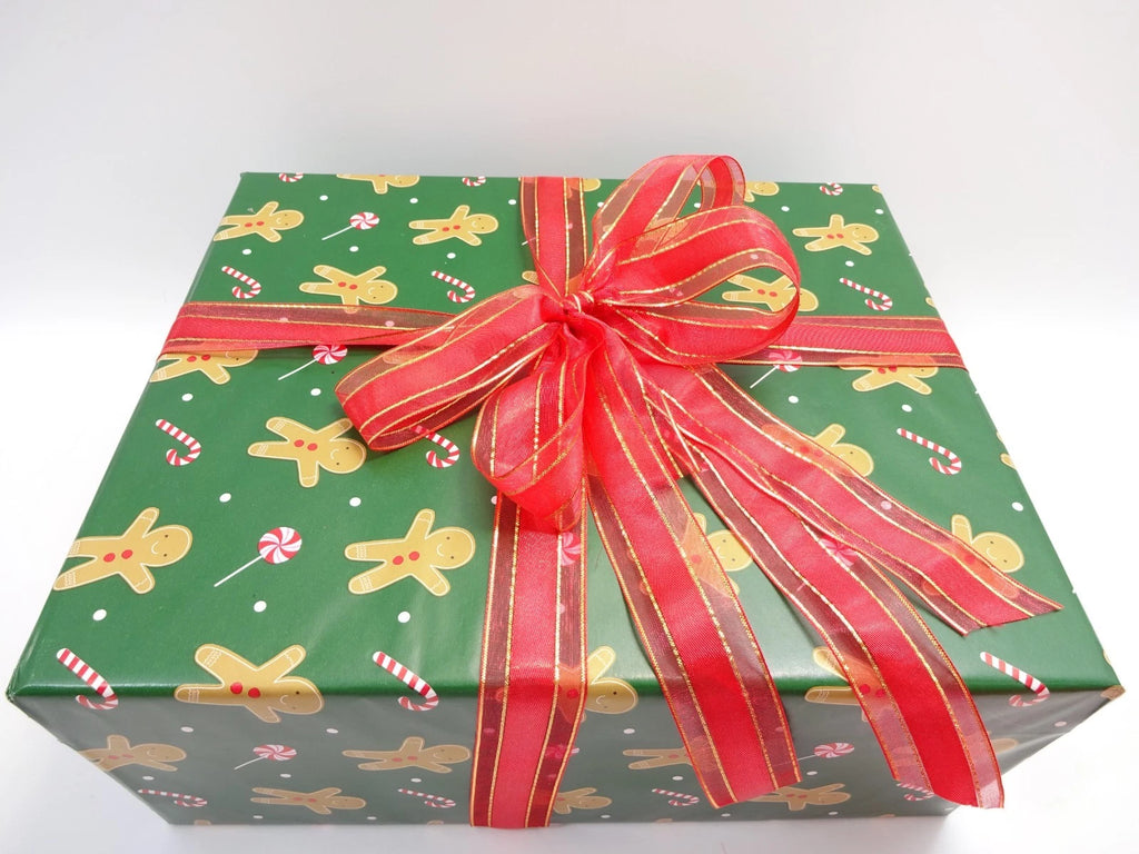 Green gift box with gingerbread men pattern and red ribbon on a white background