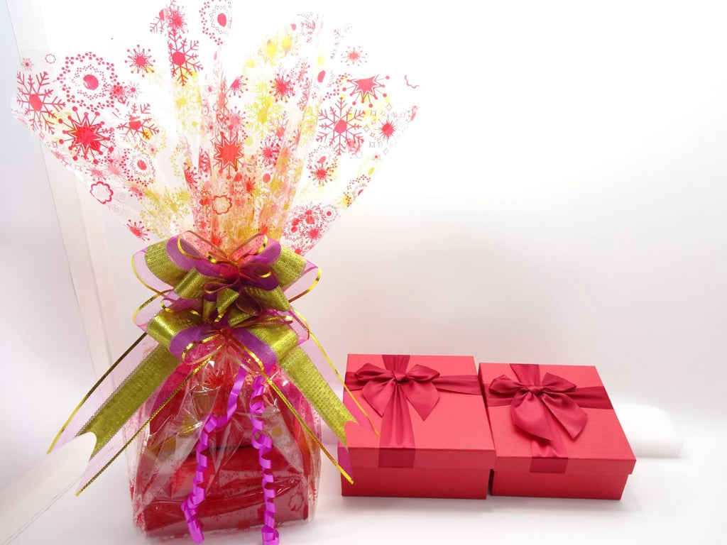 Decorative bouquet with colorful ribbons next to two red gift boxes on a white background