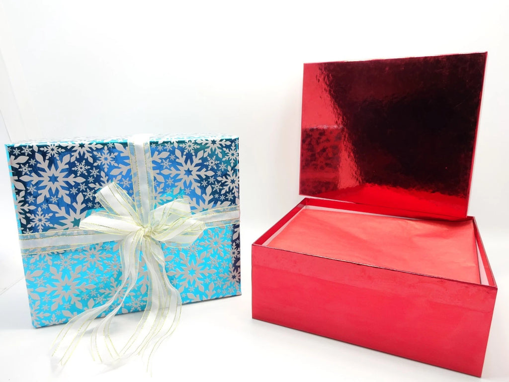 Open gift box with red tissue wrapping covering Maybelline beauty products inside