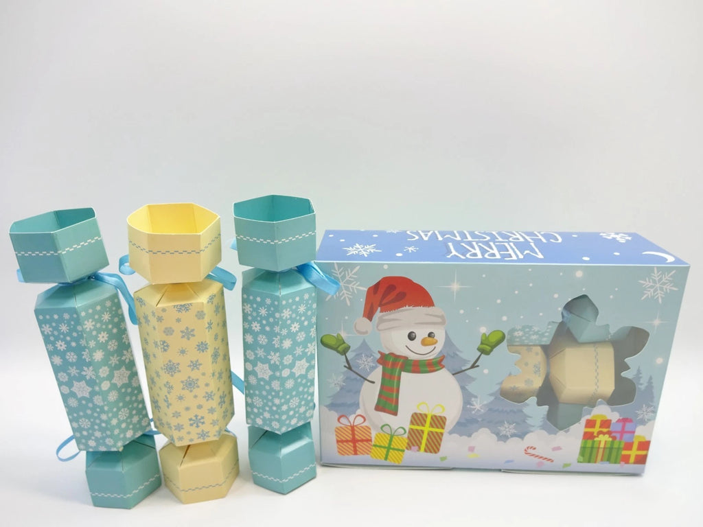 Snowflake-patterned Maybelline beauty crackers beside “Merry Christmas” snowman gift box