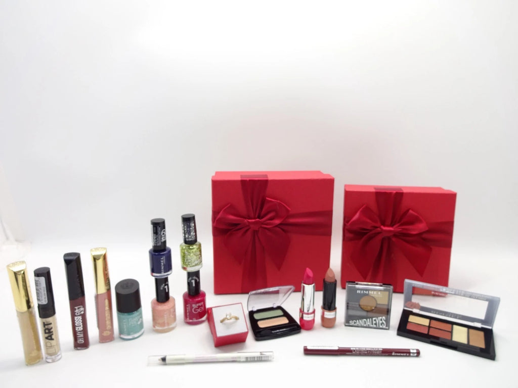 Collection of makeup products including lipsticks, nail polishes, and eyeshadows in front of red gift boxes on a white background.