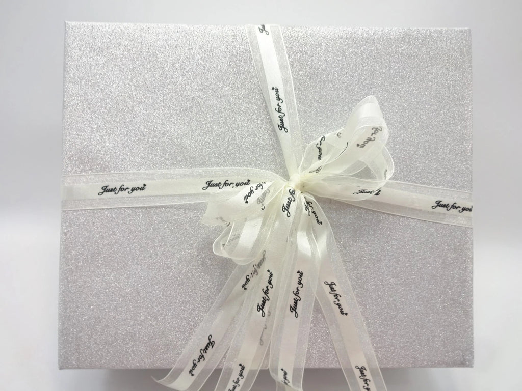 Angled view of silver glitter Maybelline 26pc Beauty Gift Box with decorative ribbon