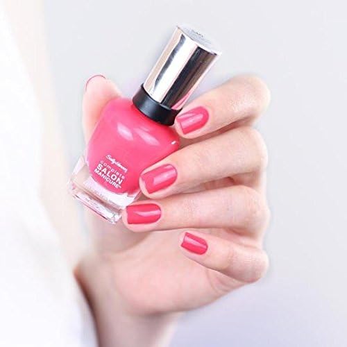 Hand holding a bottle of pink nail polish with matching nails on a white background