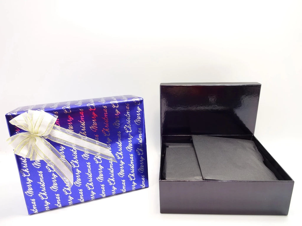 Open glossy black presentation box next to luxury Christmas-wrapped gift box with white and gold bow.