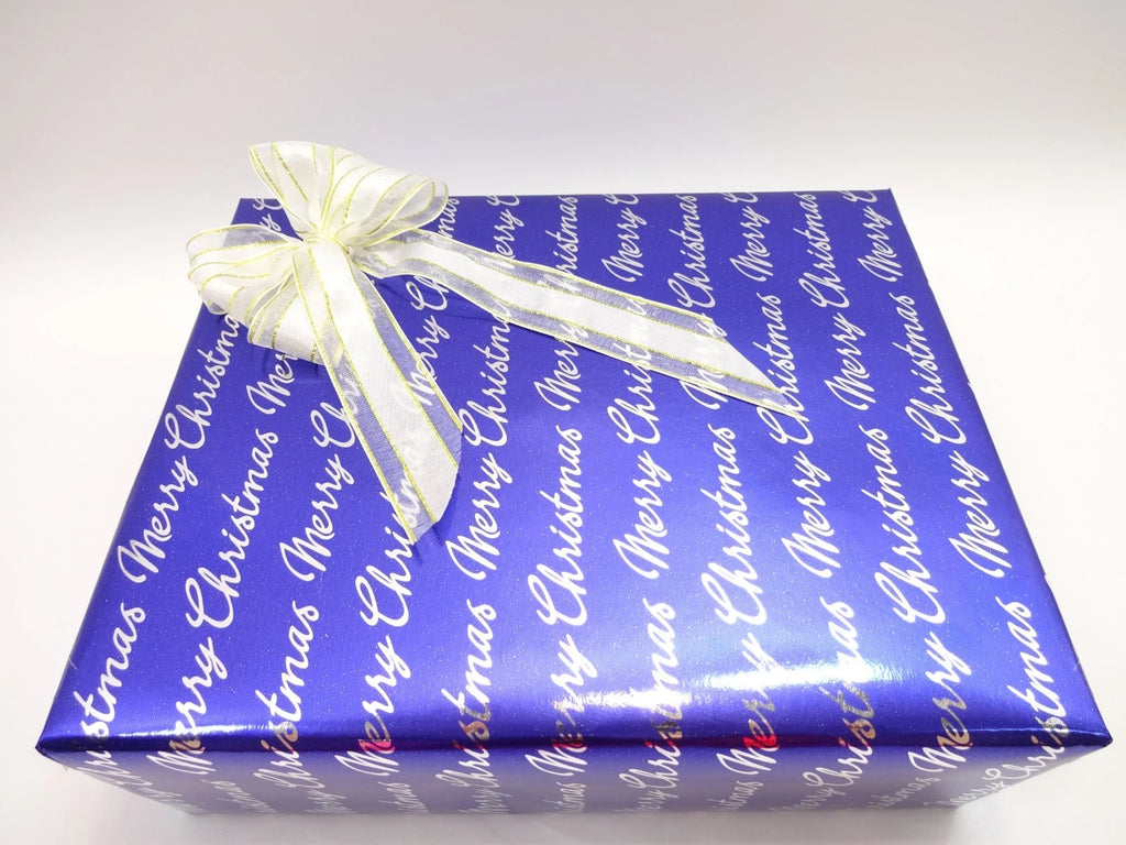 Angled view of luxury men’s Christmas gift box in blue wrapping paper with white and gold bow detail.