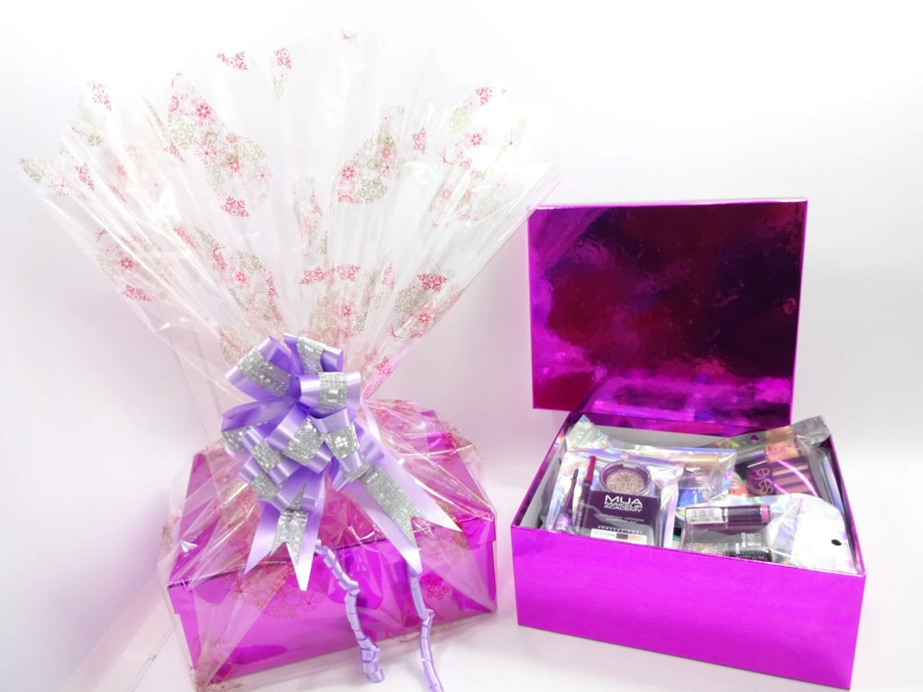 Glamorous pink gift box with purple bow and makeup products displayed inside