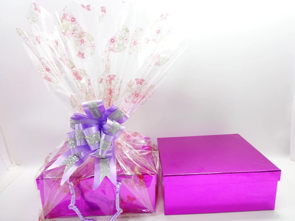Closed pink luxury gift box beside fully wrapped Christmas 2025 beauty hamper