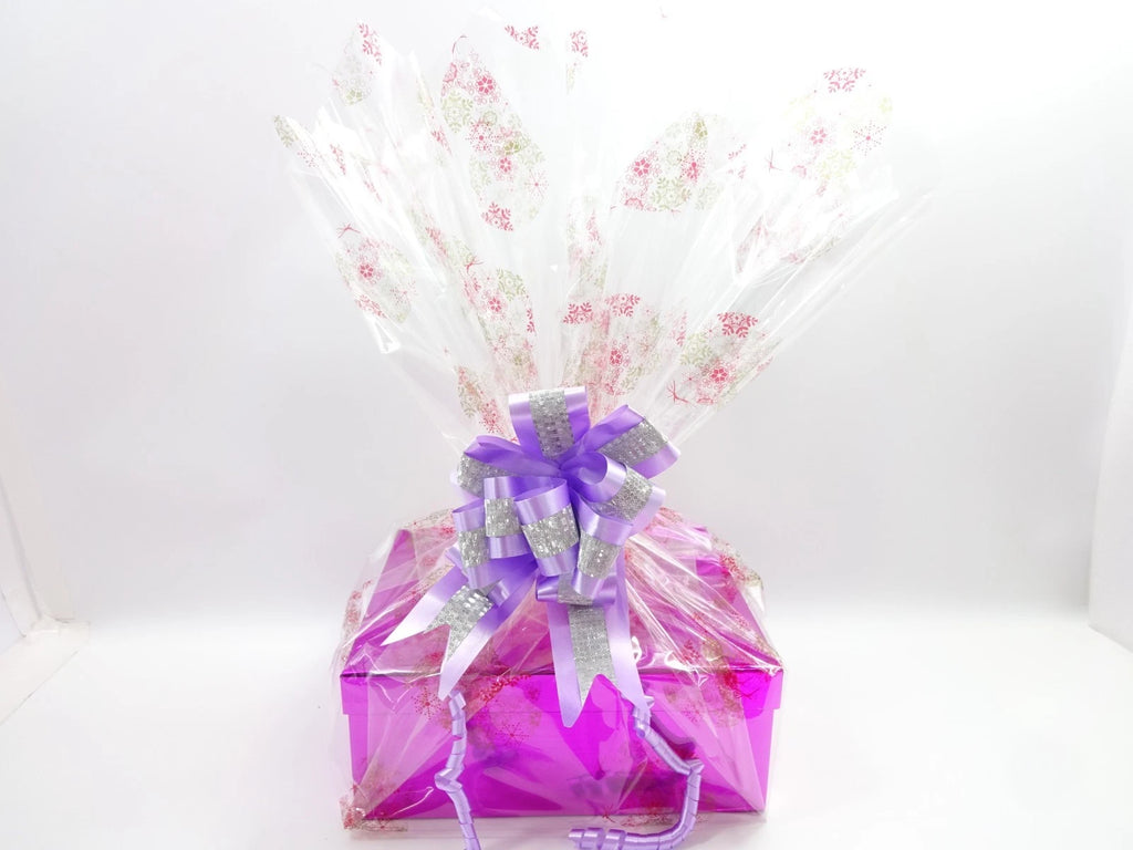 Elegant Christmas hamper wrapped with purple bow beside metallic pink gift box