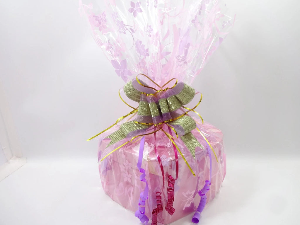 Close-up of luxury beauty hamper wrapped with shimmering gold and purple ribbon bow