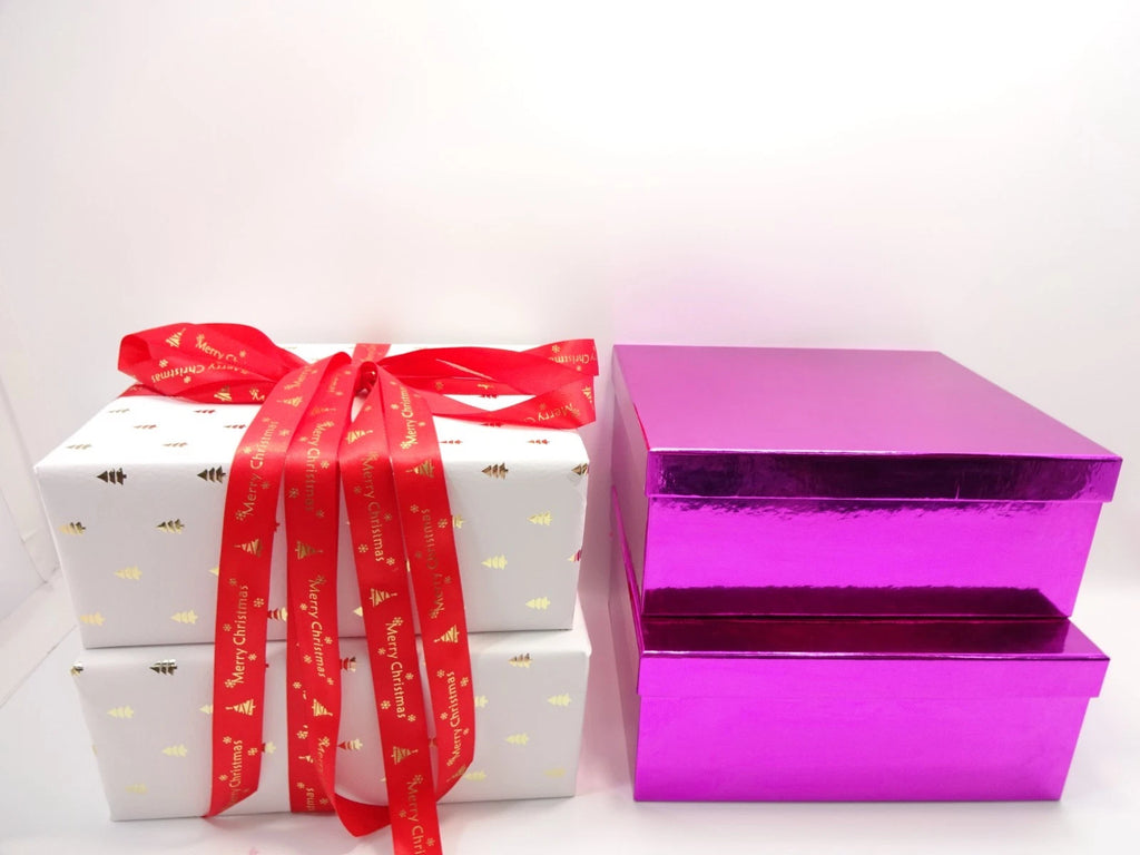 Side-by-side view of white Christmas gift box with red ribbon and metallic pink gift boxes.