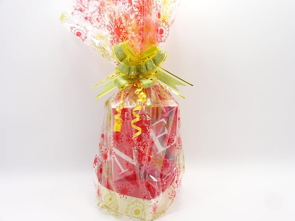 Gift hamper wrapped in cellophane with gold ribbon, featuring All Me perfume and heart-shaped gift box