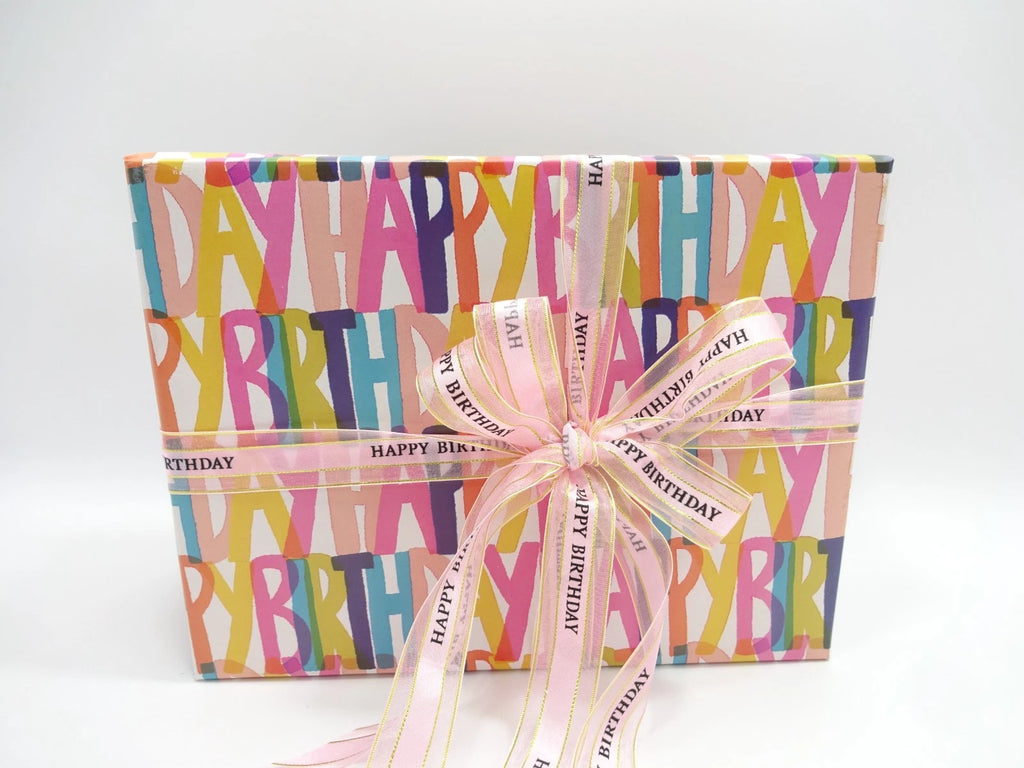 Front view of Happy Birthday makeup gift box with bold colorful lettering and pink bow