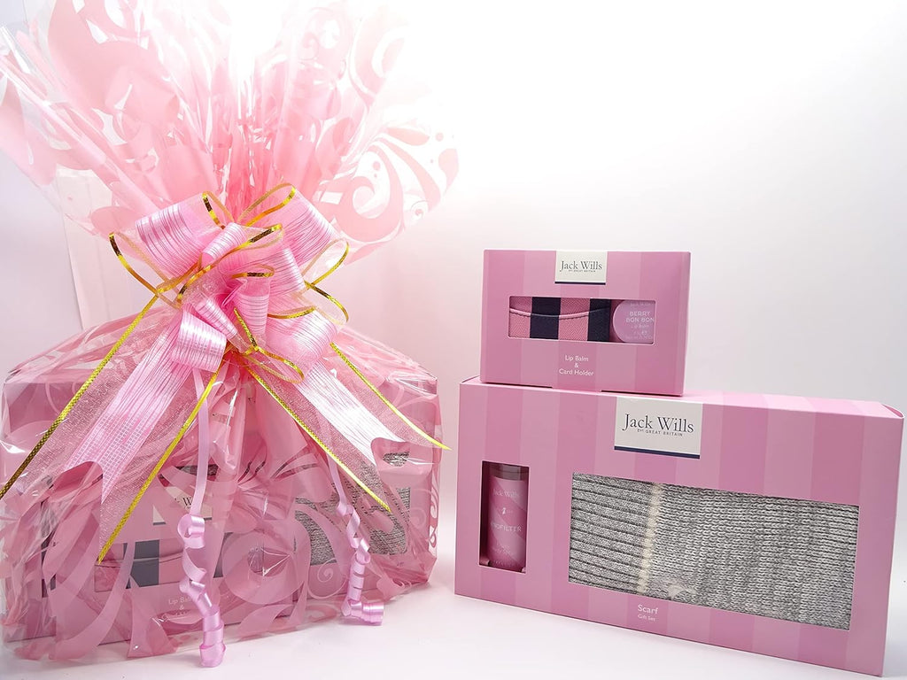 Jack Wills ladies gift hamper wrapped in pink cellophane with elegant pink and gold ribbon showing showing scarf, fruity body spray, lip balm, and card holder
