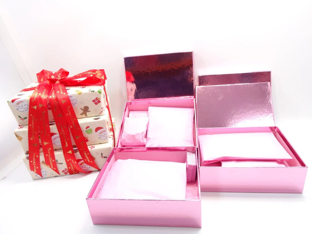 Open pink boxes with tissue-wrapped beauty items next to wrapped Christmas box