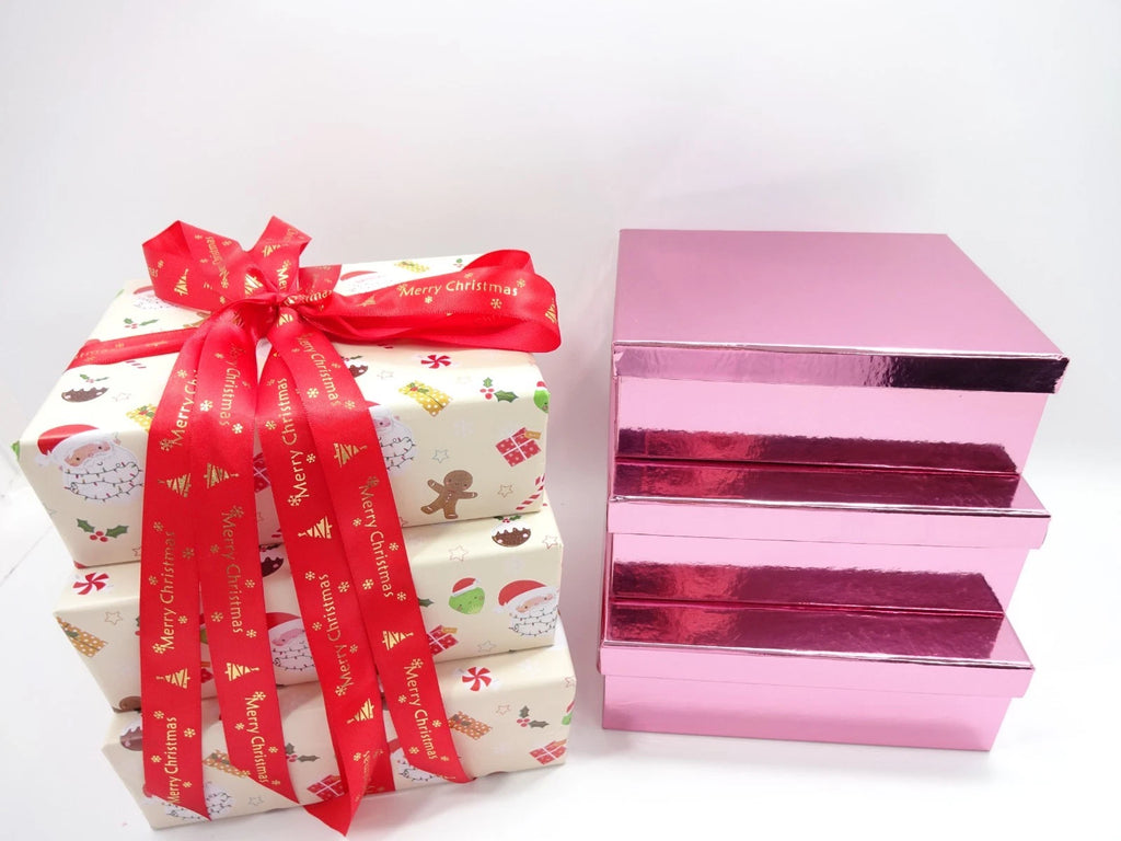 Stacked Christmas gift box beside three metallic pink drawer boxes