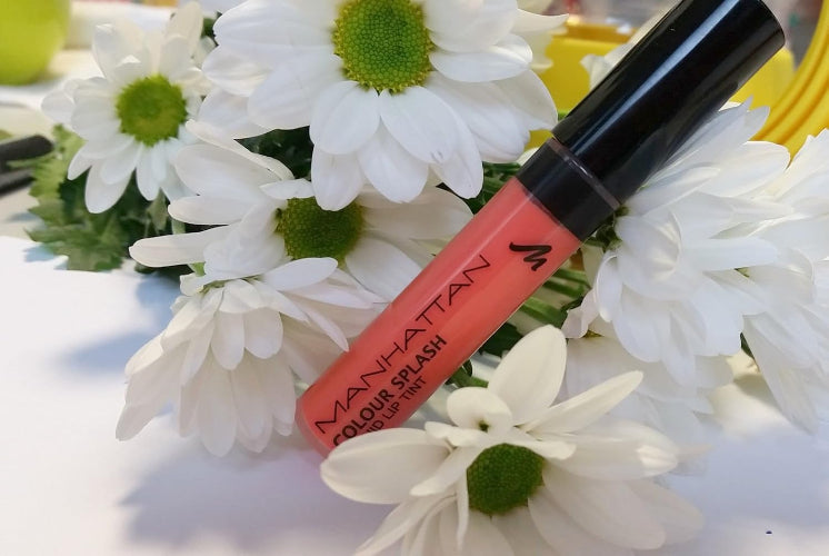 Manhattan Colour Splash Liquid Lip Tint 93C My Mandarine in coral-orange shade placed against white daisies for a vibrant summer look