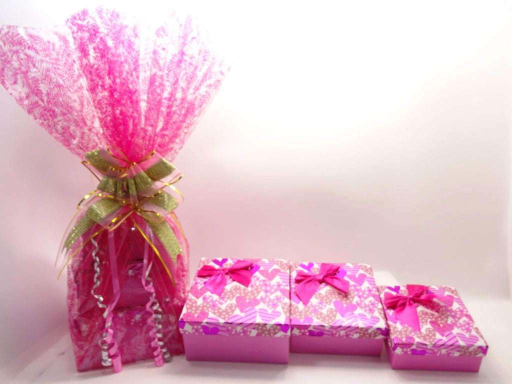 Three pink gift boxes open to reveal pink tissue wrapping inside