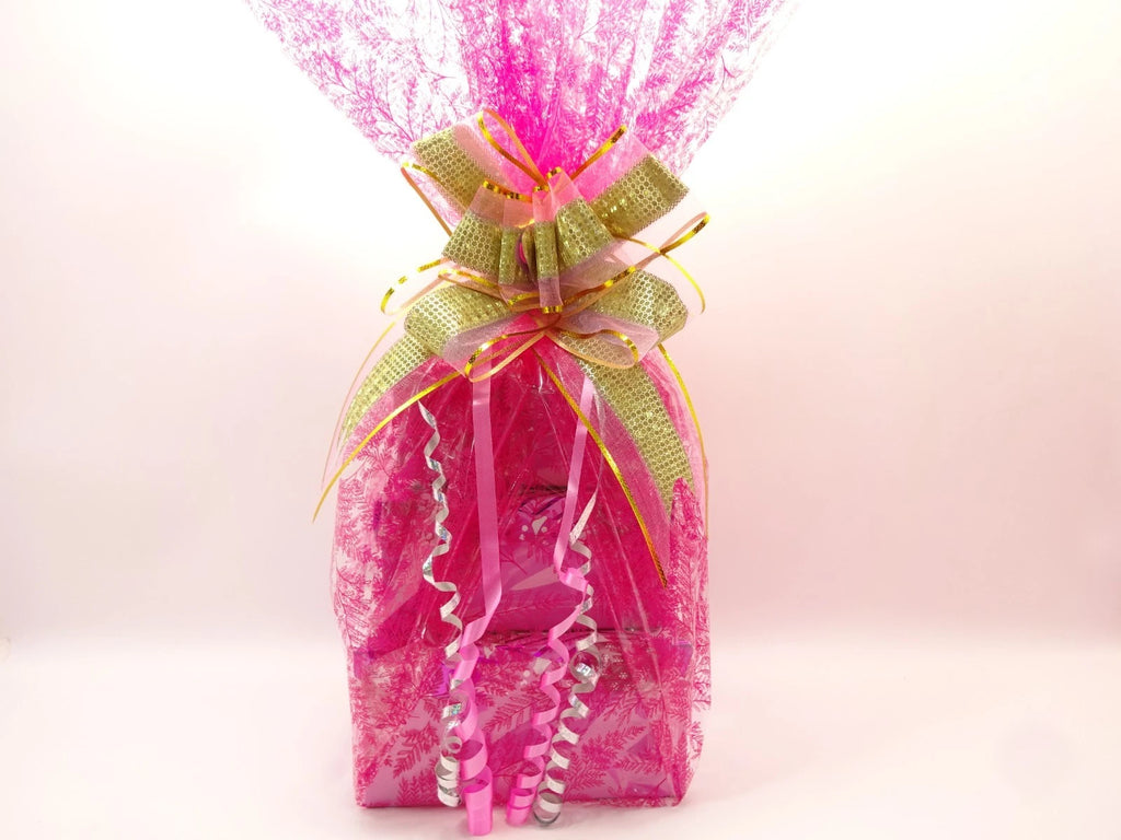 Beautifully wrapped Max Factor makeup gift hamper in pink lace cellophane with green and gold ribbon bow
