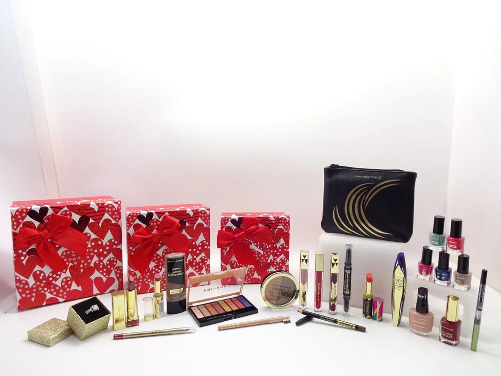 Stacked red heart print gift boxes with red satin bows beside wrapped hamper