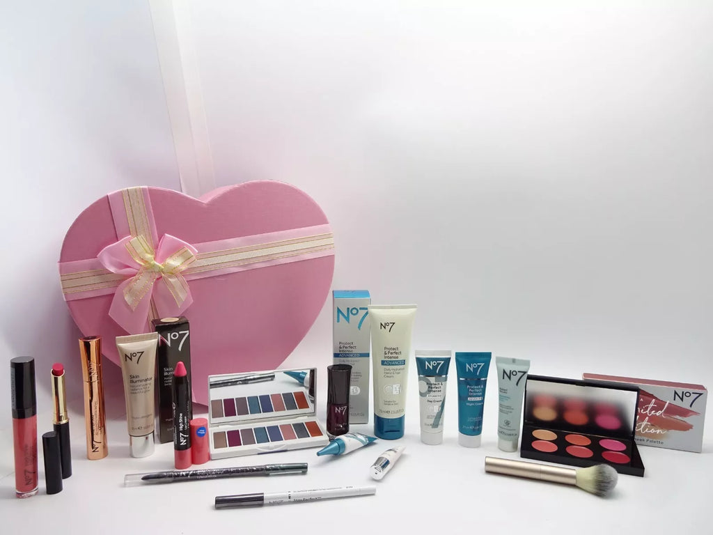 No7 gift set with skincare and makeup items arranged in front of a pink heart-shaped box, featuring serums, lipsticks, and makeup palette.