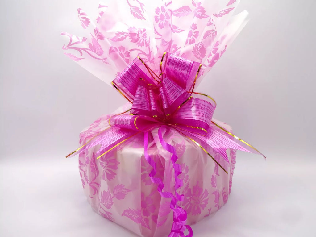 Pink heart-shaped box wrapped in a decorative pink floral cellophane and topped with a luxurious pink bow, perfect for gifting.