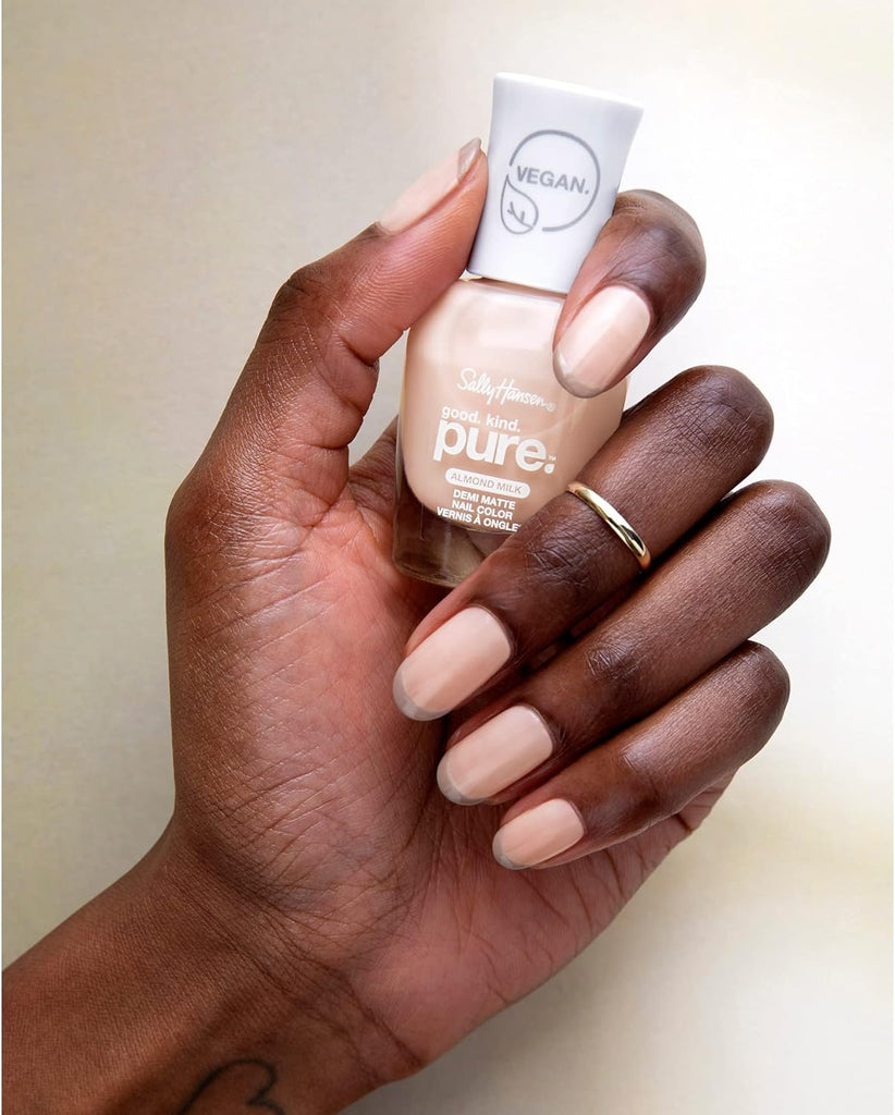 Hand holding Sally Hansen Good Kind Pure vegan nail polish in Almond Milk shade, showing smooth nude coverage on natural nails