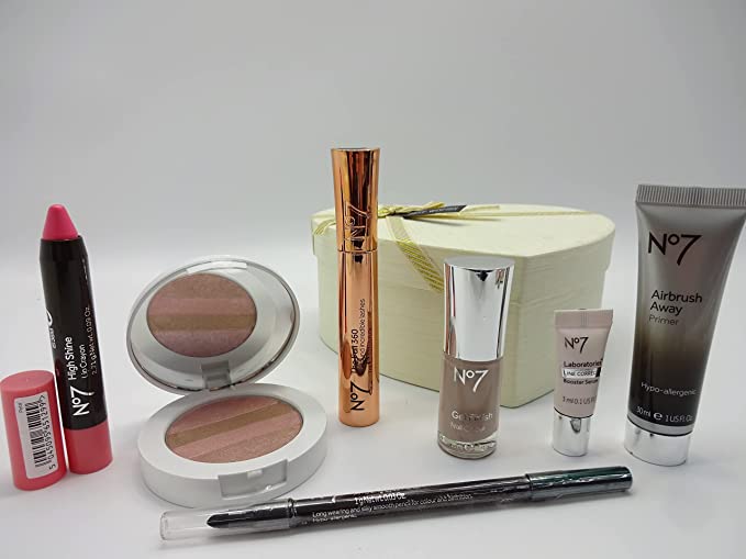 A collection of No7 makeup products displayed beside the white heart-shaped box, featuring lip crayon, mascara, and primer.